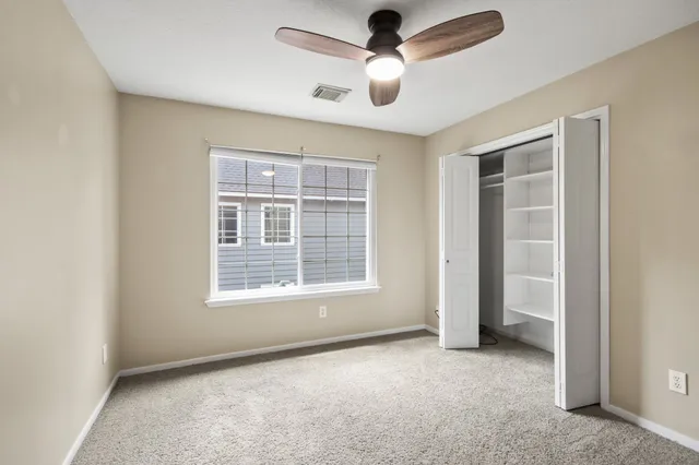 an empty room with ceiling fan and windows
