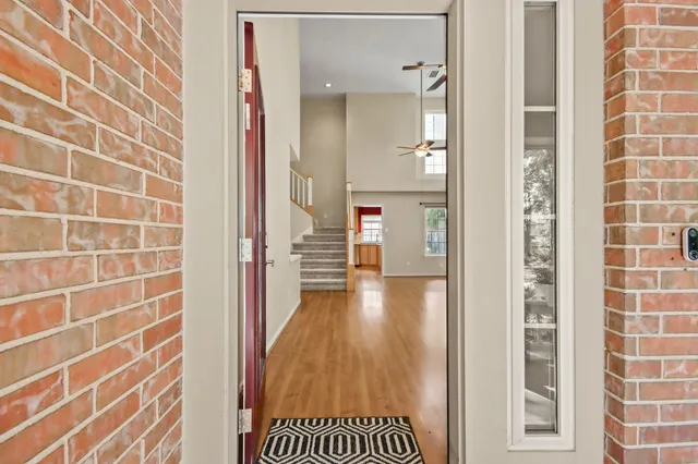 a view of a hallway with wooden floor and a bathroom