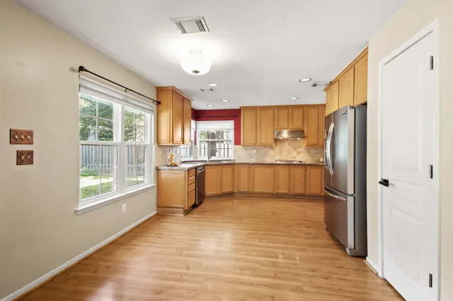 a kitchen with stainless steel appliances granite countertop a refrigerator a oven a sink dishwasher and a refrigerator with wooden floor