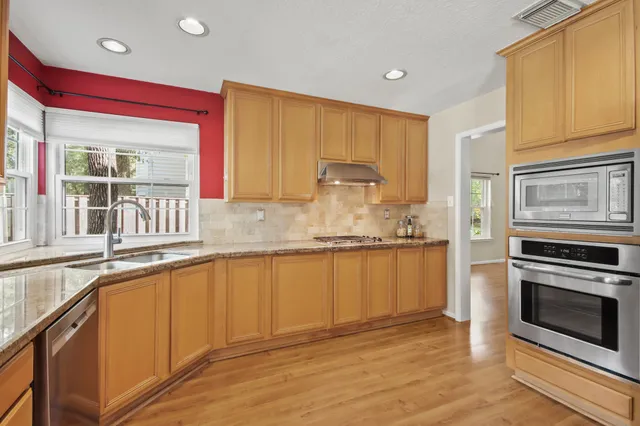 a kitchen with stainless steel appliances granite countertop a stove a sink and a microwave