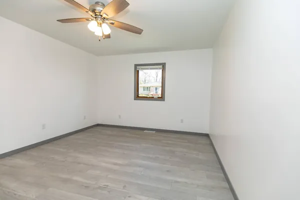 an empty room with a window and a fan