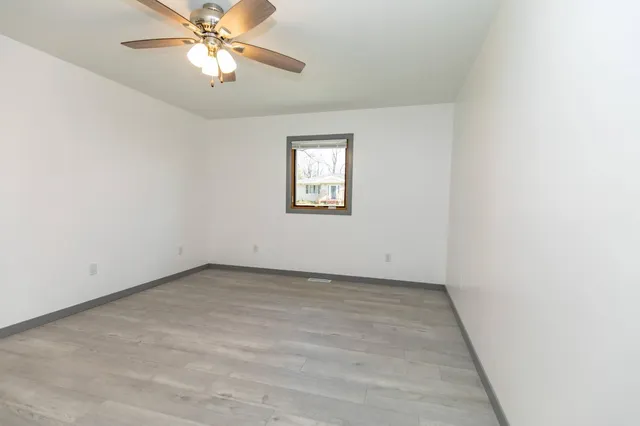 an empty room with a window and a fan