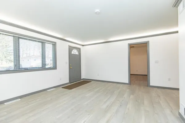 an empty room with wooden floor and windows