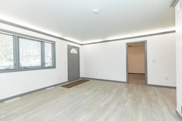 an empty room with wooden floor and windows