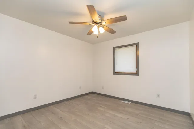 an empty room with a window and a fan