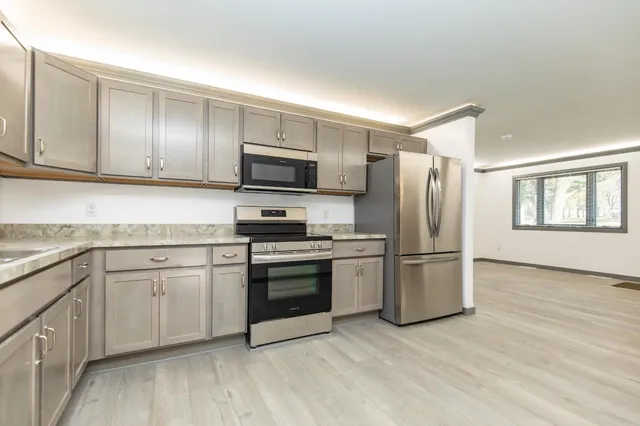 a kitchen with cabinets stainless steel appliances and a window