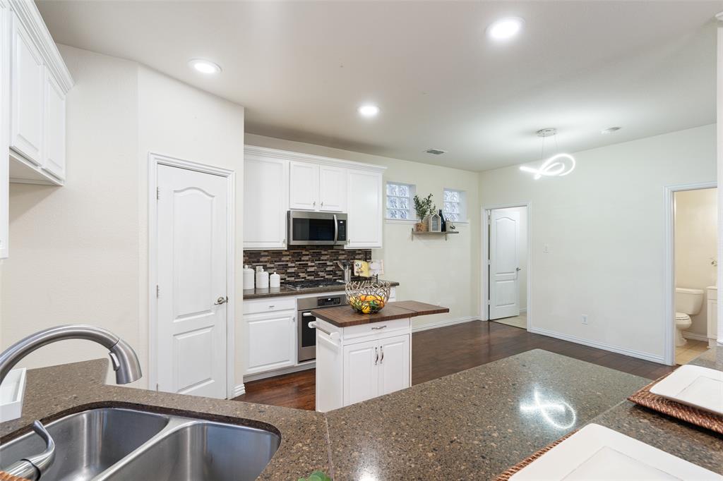 7113 Occidental Road Plano, TX 75025 - Photo 14 of 35 a kitchen with stainless steel appliances kitchen island granite countertop a refrigerator and a stove top oven