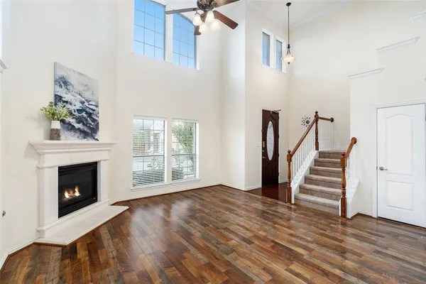 a view of an empty room with wooden floor fireplace and a window