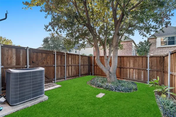 a view of a backyard with a large tree and wooden fence