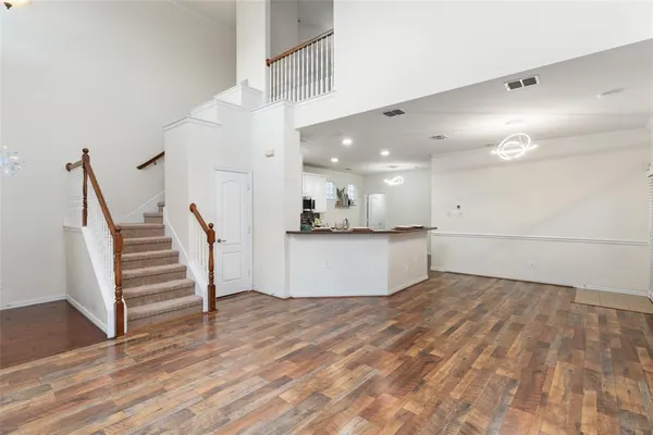 a view of an empty room with wooden floor and stairs