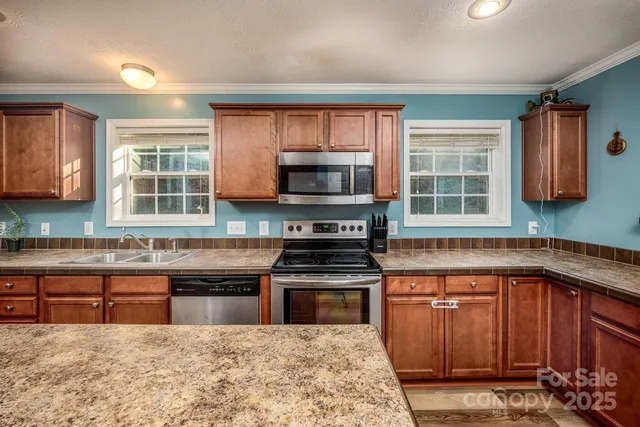 a kitchen with stainless steel appliances granite countertop a stove a sink and a microwave