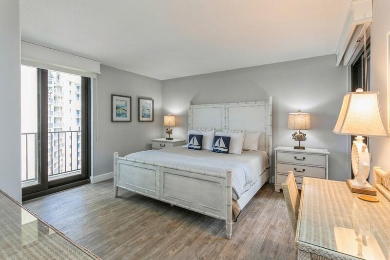 100 Ocean Trail Way, Unit 1010 Jupiter, FL 33477 - Photo 18 of 40 a spacious bedroom with a bed and a lamp on table with wooden floor