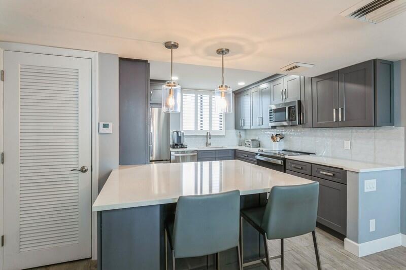 100 Ocean Trail Way, Unit 1010 Jupiter, FL 33477 - Photo 4 of 40 a large kitchen with kitchen island a dining table chairs cabinets and a sink