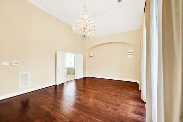 a view of an empty room with wooden floor and a large window