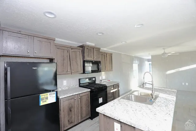 a kitchen with granite countertop a refrigerator a sink a stove a microwave and island