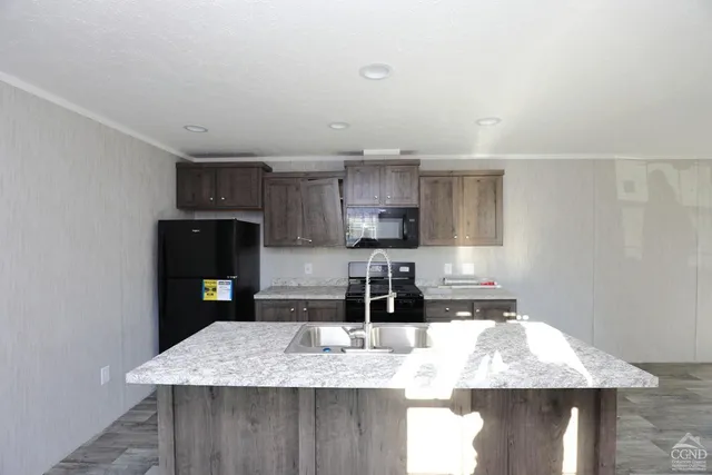 a kitchen with kitchen island granite countertop a sink a stove and refrigerator
