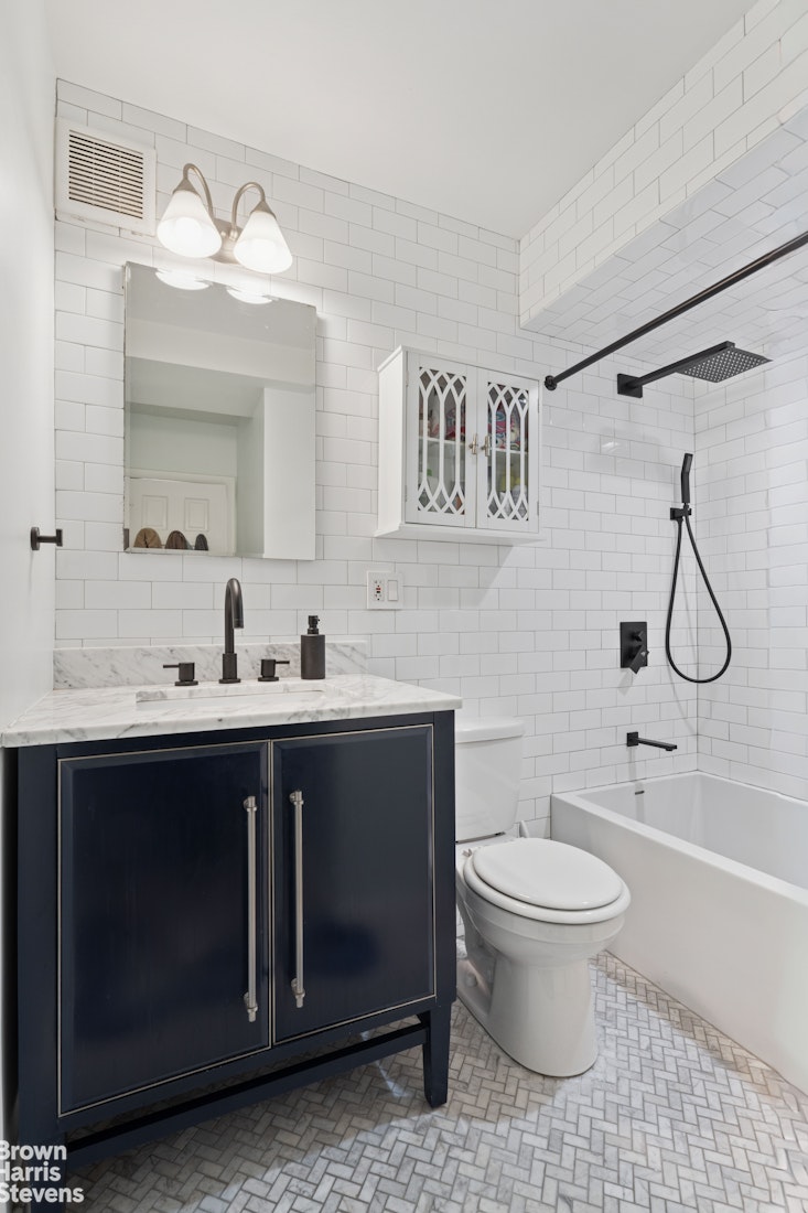 383 Grand Street, Unit M2002 Manhattan, NY 10002 - Photo 9 of 12 a spacious bathroom with a sink a toilet and a large mirror
