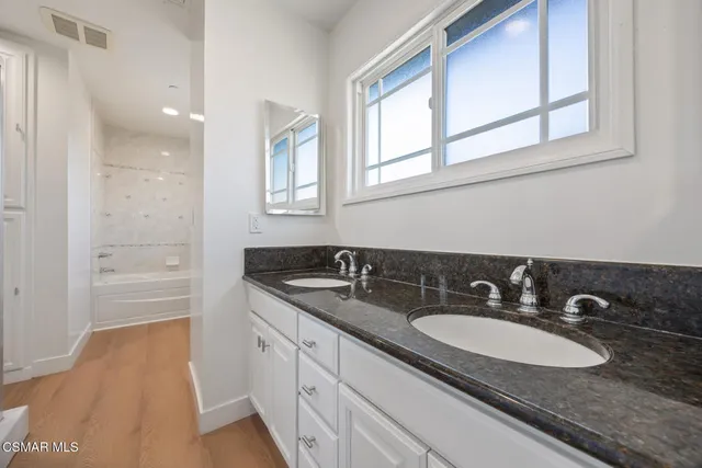 a bathroom with a sink double vanity granite tub and a mirror