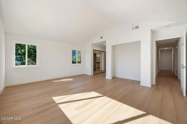 a view of an empty room with window and wooden floor