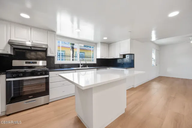 a kitchen with stainless steel appliances kitchen island granite countertop a stove a sink and a microwave