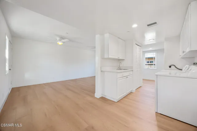 a view of a kitchen with white cabinets and wooden floor