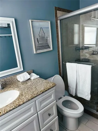 a bathroom with a granite countertop toilet sink and mirror