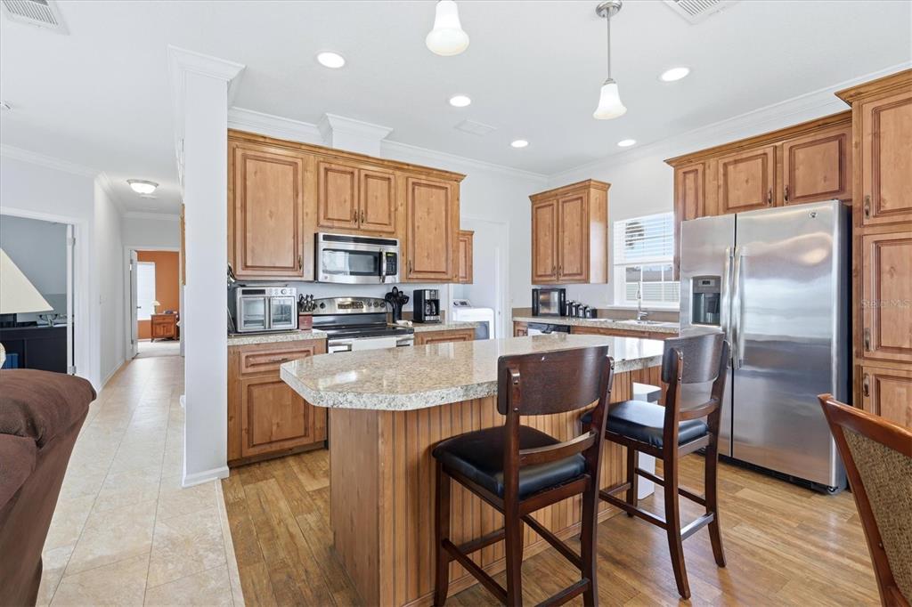 1 Meadow Circle Ellenton, FL 34222 - Photo 16 of 43 a kitchen with stainless steel appliances granite countertop a refrigerator a stove top oven a sink dishwasher a dining table and chairs with wooden floor