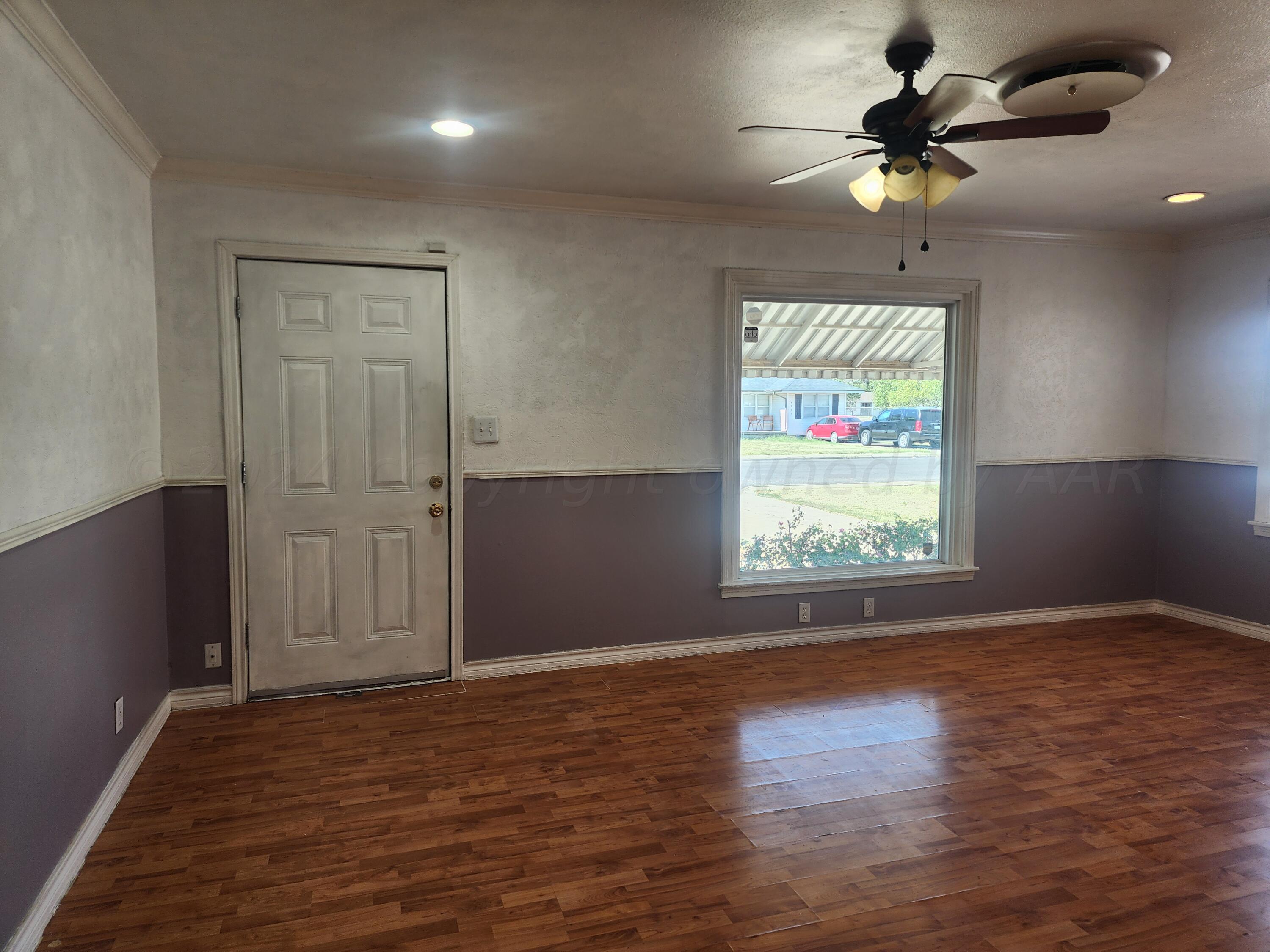 4003 Cline Road Amarillo, TX 79110 - Photo 3 of 17 an empty room with wooden floor fan and windows