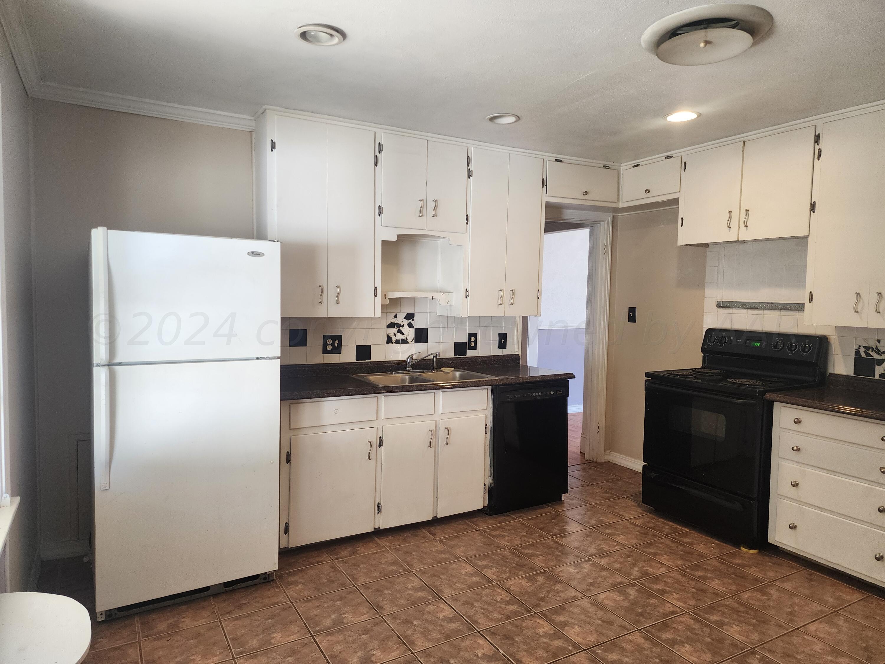 4003 Cline Road Amarillo, TX 79110 - Photo 5 of 17 a kitchen with refrigerator a stove a sink and white cabinets