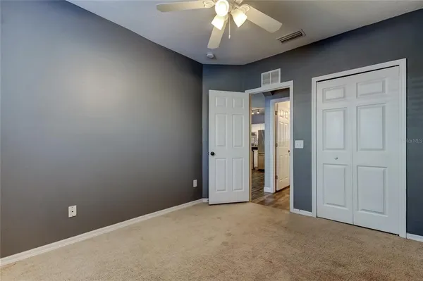 an empty room with a chandelier fan and closet area