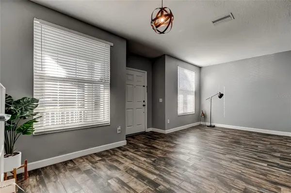 a view of an empty room with a window and wooden floor