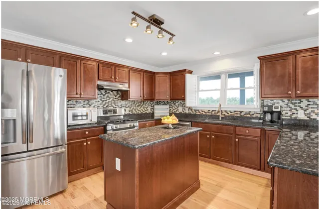 a kitchen with stainless steel appliances granite countertop a refrigerator a stove a sink a center island and a refrigerator