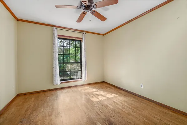 an empty room with wooden floor chandelier fan and windows