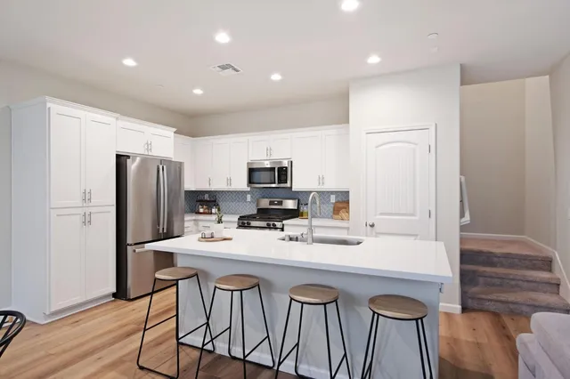 a kitchen with stainless steel appliances granite countertop a sink a stove a refrigerator and cabinets