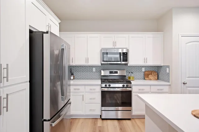 a kitchen with white cabinets and stainless steel appliances