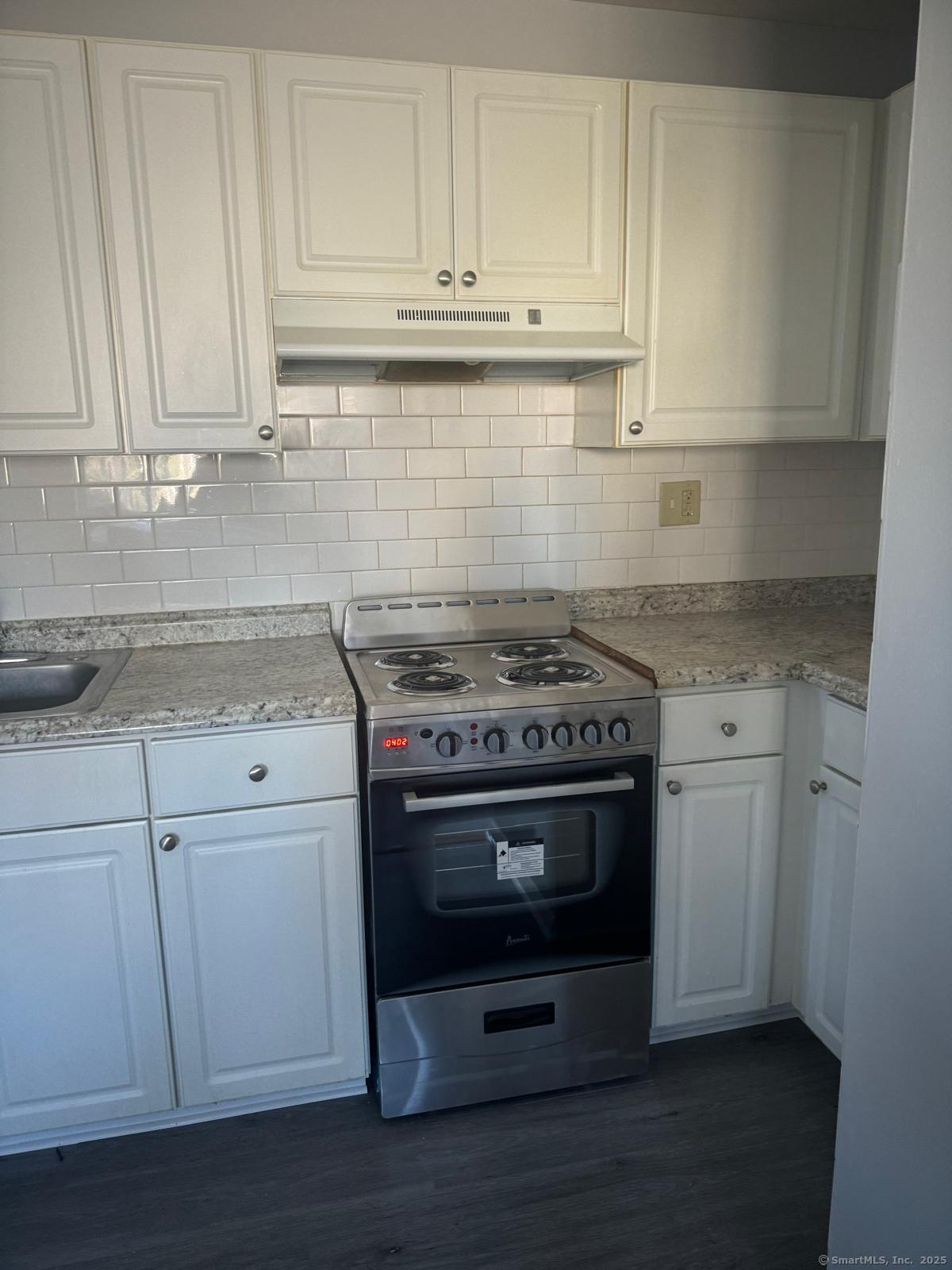 a kitchen with granite countertop white cabinets and stainless steel appliances