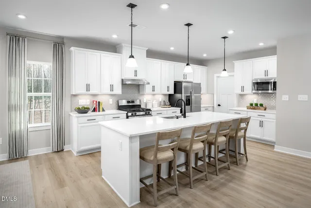 a large kitchen with kitchen island a large counter space a sink appliances and a large window