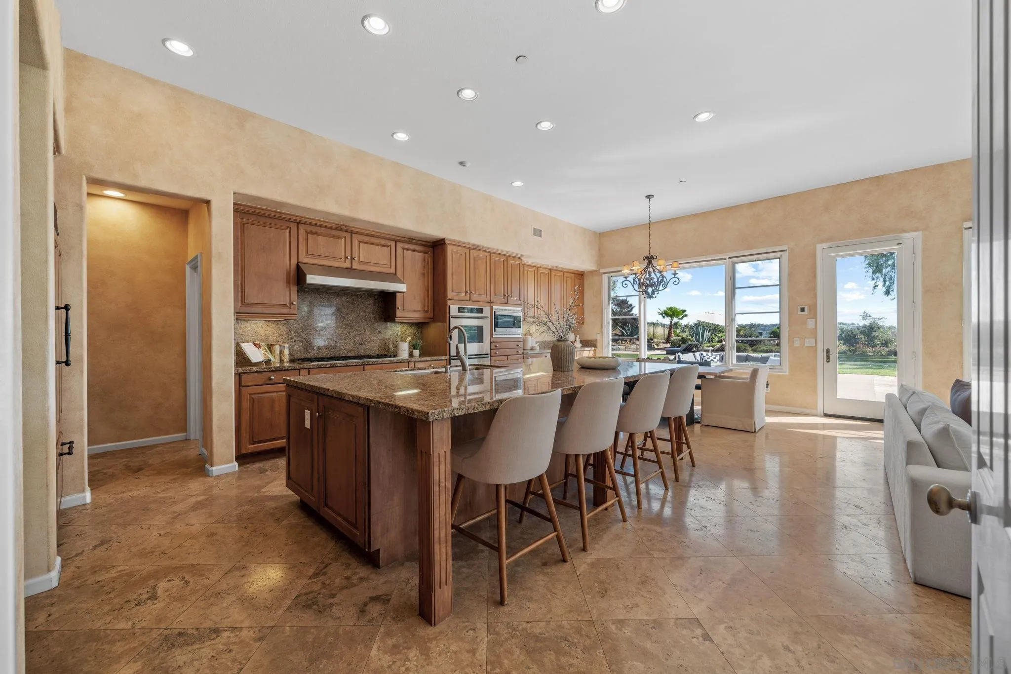 17813 La Amapola Rancho Santa Fe, CA 92067 - Photo 12 of 30 a kitchen with stainless steel appliances granite countertop a table chairs and a refrigerator