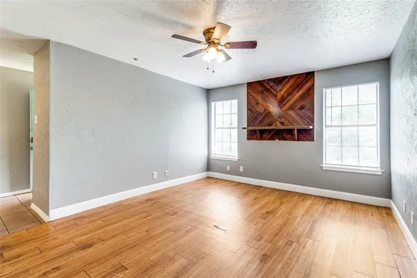 an empty room with window and chandelier fan