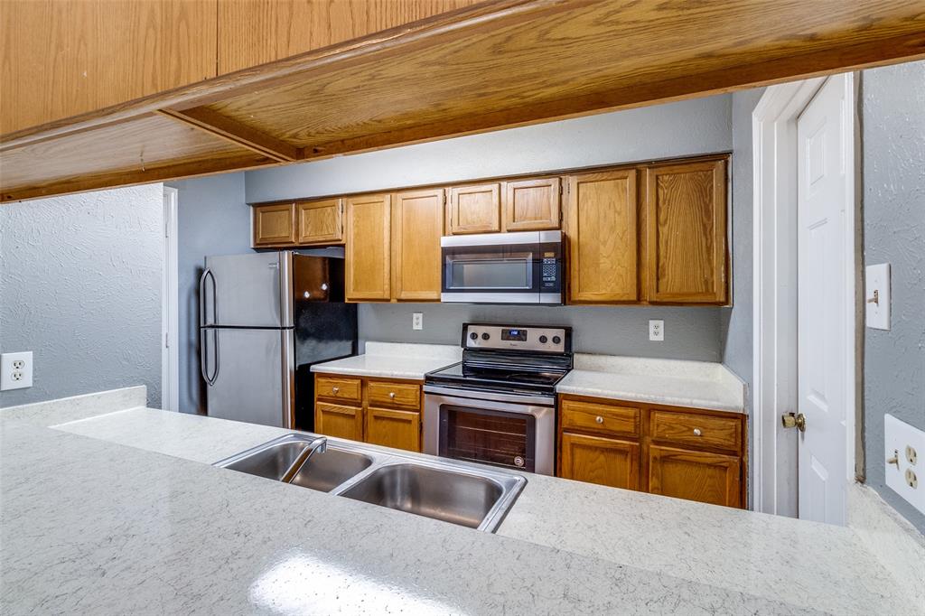 2354 Little Pocket Road, Unit B Dallas, TX 75228 - Photo 8 of 12 Kitchen featuring a textured wall, stainless steel appliances, and wood finish cabinets