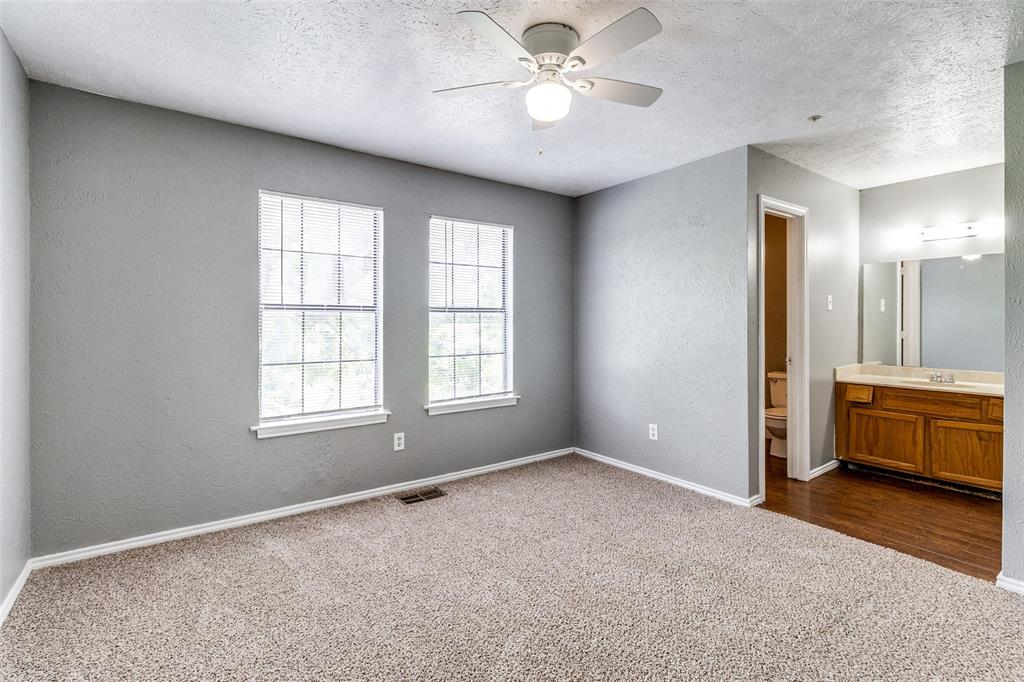 2354 Little Pocket Road, Unit B Dallas, TX 75228 - Photo 9 of 12 Unfurnished bedroom featuring a textured wall, dark colored carpet, ensuite bathroom, a textured ceiling, and a ceiling fan