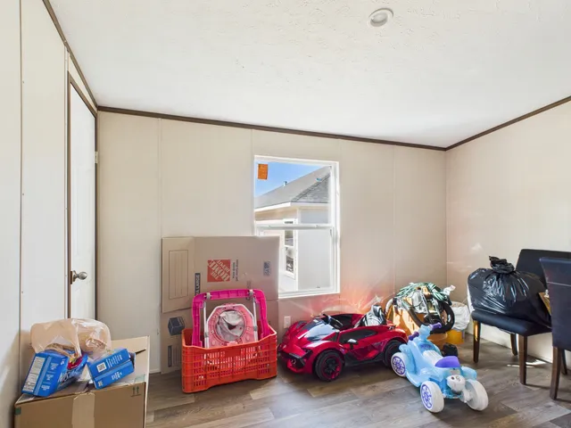 a bedroom with a bed next to a window with dresser and closet