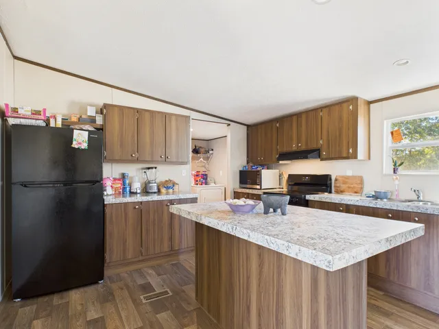 a kitchen with a refrigerator a stove a sink dishwasher and wooden cabinets with wooden floor