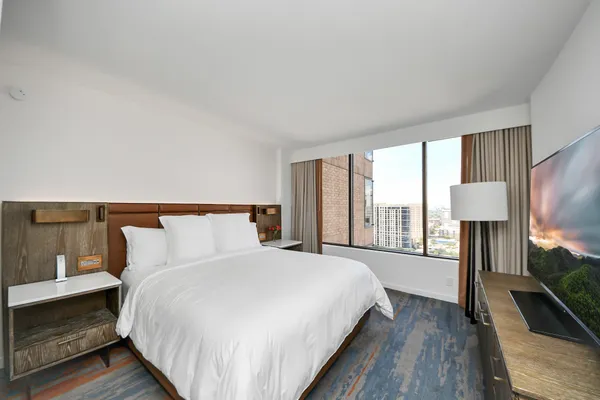 a spacious bedroom with a bed and a lamp on table