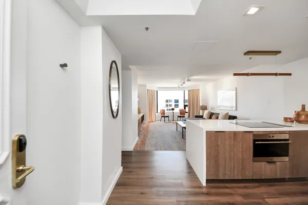 a living room with stainless steel appliances furniture a rug and a kitchen view