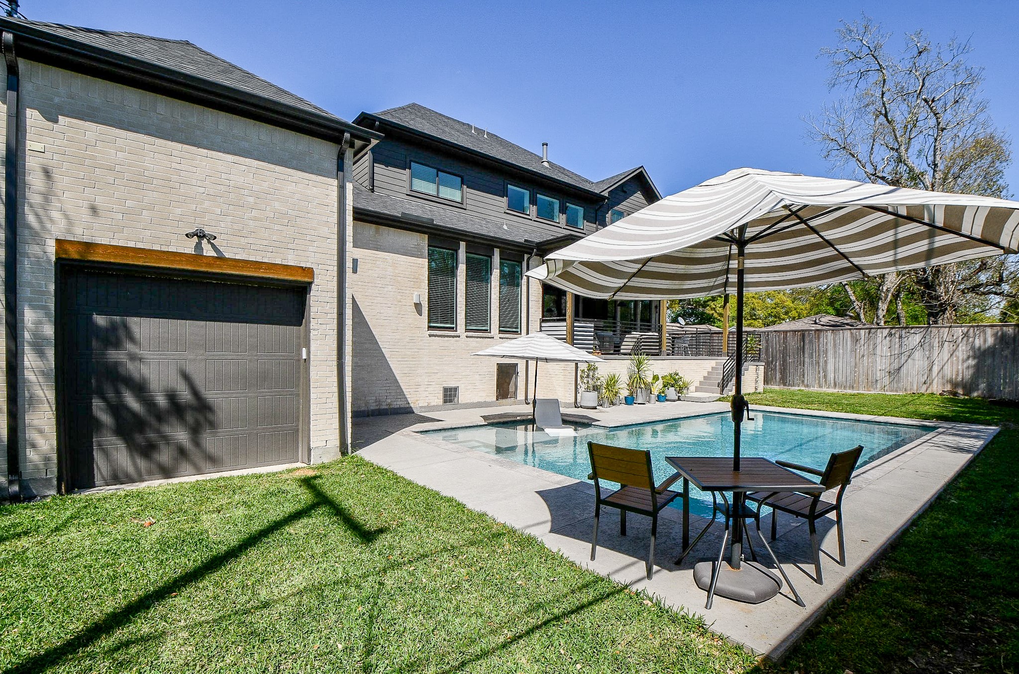 5315 Jason Street Houston, TX 77096 - Photo 15 of 39 Modern home with a spacious backyard featuring a pool, patio area with umbrellas, and well-green space surrounds pool area. Ideal for outdoor relaxation and entertainment. Garage door gives bathroom access to swimmers.
