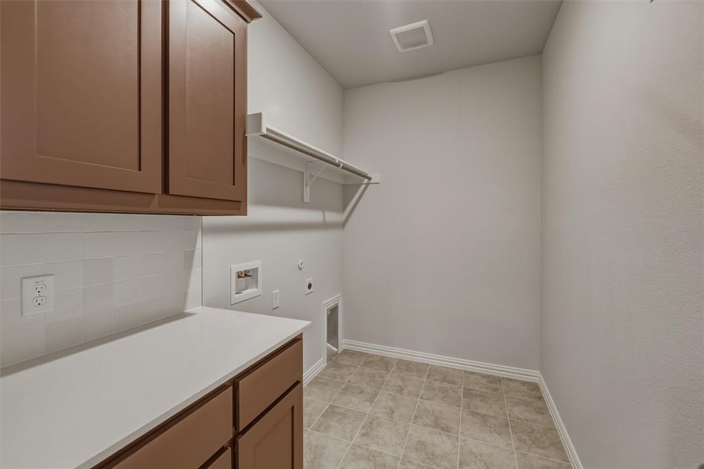1325 Frio Drive Springtown, TX 76082 - Photo 17 of 24 Laundry area featuring brown cabinetry, white countertop, white subway tile backsplash, and tile flooring
