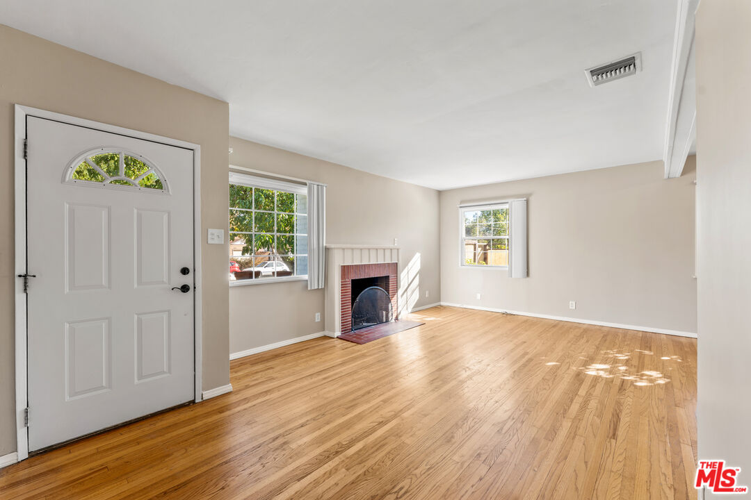 6327 Ranchito Avenue Valley Glen, CA 91401 - Photo 9 of 46 an empty room with windows a fireplace and wooden floor