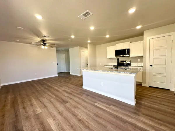 a large kitchen with kitchen island a sink dishwasher a stove and a refrigerator with wooden floor