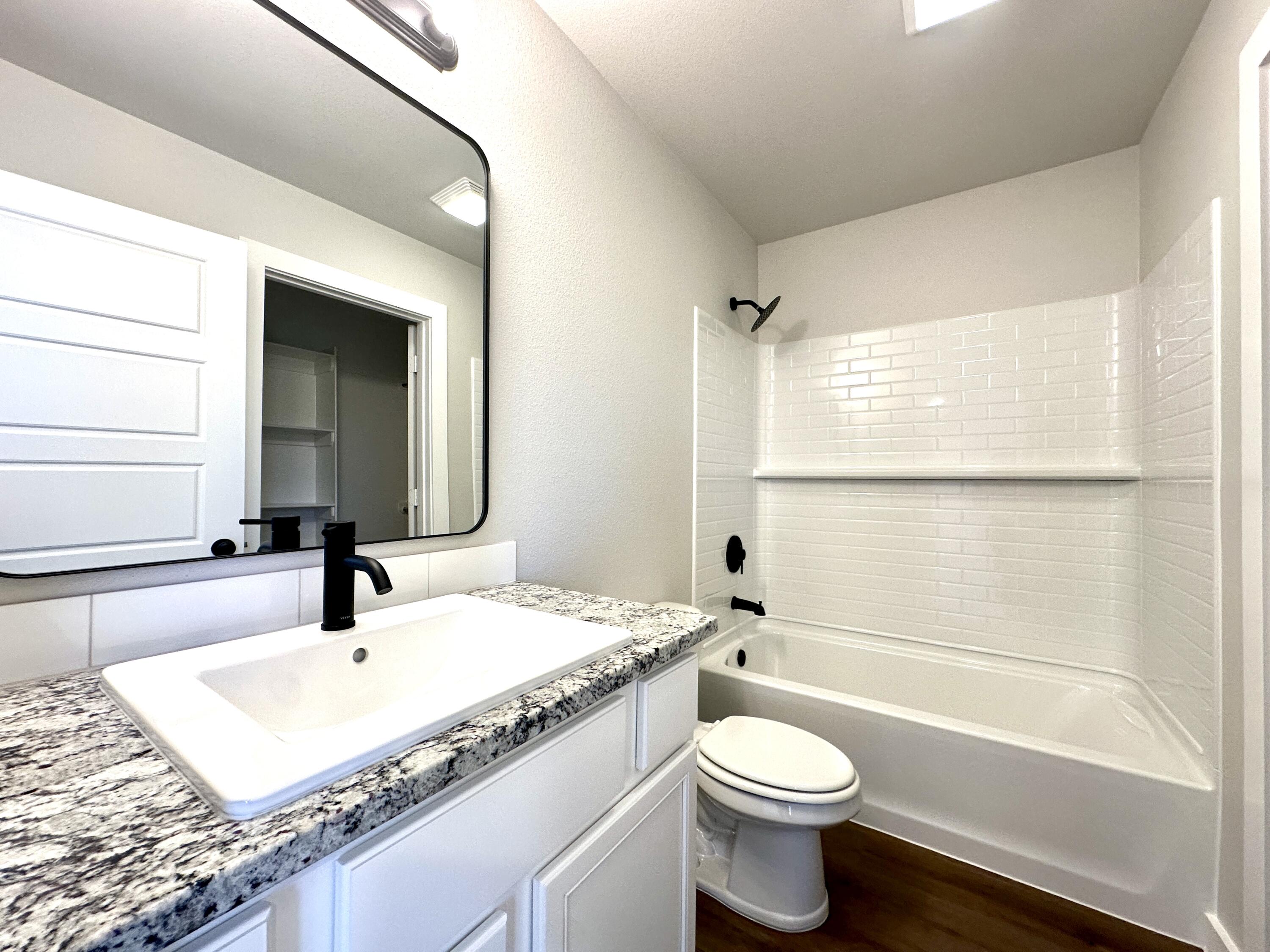 5528 Princeton Street Lubbock, TX 79416 - Photo 8 of 10 a bathroom with a granite countertop sink toilet and shower